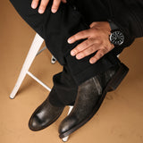 Man weaing a crackled black botin with braided arros and a diamond shape stud on the side. 