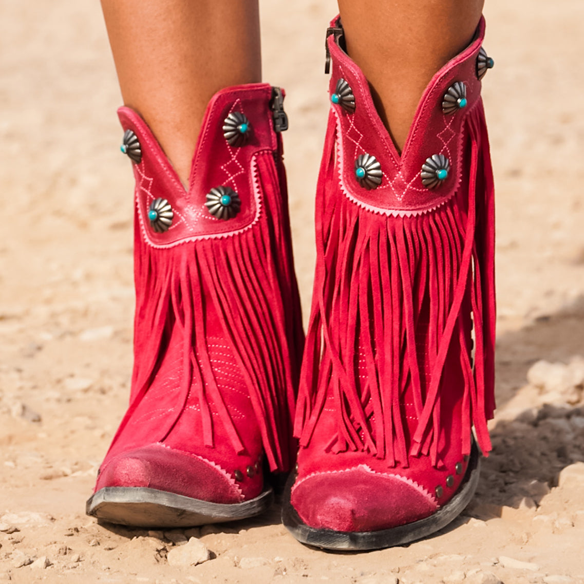 Pink suede fringe boots worn by a person in the desert