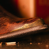 Whiskey botin with a geometric pattern embroidered on the shaft and studs on the heel. Angled to see the toe cap